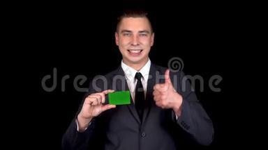年轻的商人出示了一张银行绿卡，并用他的手表现得像。 彩色绿卡。
